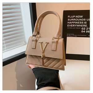 Detail of beige PU leather handbag featuring top handle and V-shaped metal buckle with tassels