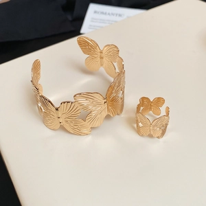 Detailed view of golden butterfly bracelet and ring set with textured metal wings
