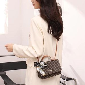 Classic brown monogram handbag with silk scarf and leather strap on a female model
