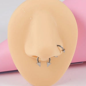 Detailed close-up of G23 titanium silver septum and nostril rings with spike ends