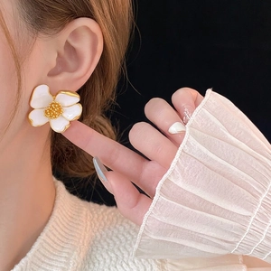 Vintage white floral stud earrings with gold metal edges worn by a model in close-up