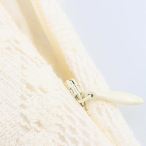 Gros plan d'une robe en dentelle blanc crème avec fermeture éclair invisible et texture