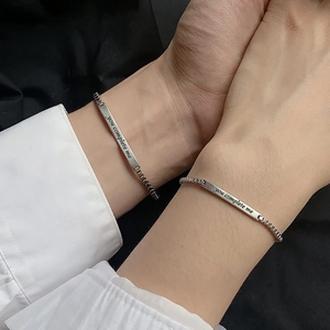 Detail view of silver couple bracelets with You Complete Me engraving on box chains