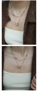 Close-up of double-layer necklace with pearls, tiger eye beads, and zircon barrel pendant