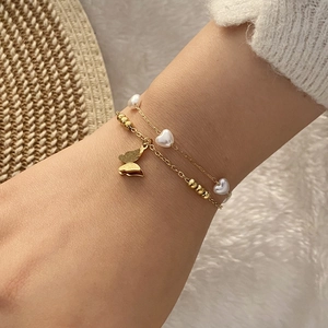 Bracelet double couche doré avec perles en forme de cœur et pendentif papillon au poignet