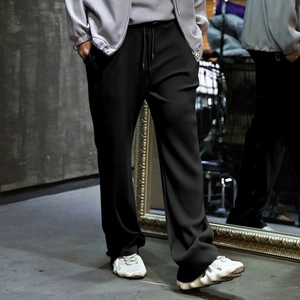 Detail shot of black pleated wide leg pants with vertical textured fabric and relaxed fit