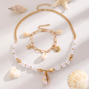 Flat lay of bohemian sea shell and starfish necklace and bracelet set with pearls