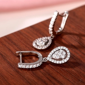 Close-up of elegant silver teardrop earrings with AAA zircon inlay on wooden surface