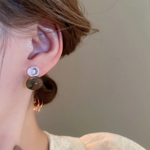 Detailed view of elegant drop earring with white shell disc and brown glass charm