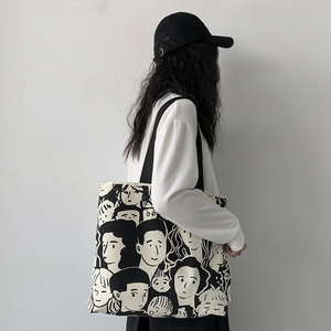 Dettaglio della grande borsa tote in tela con stampe di volti artistici e manici neri