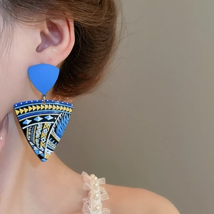Close-up of bohemian oversized triangle drop earrings with vibrant geometric paint patterns
