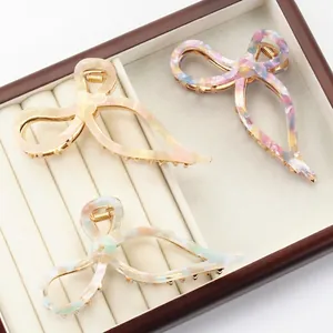 Three-piece acetate bow hair claw set with marble texture in a wooden jewelry display box