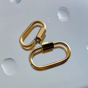 Macro detail of gold oval carabiner link with hexagonal screw lock on water drops surface