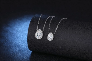 Macro detail of pear-cut moissanite pendant with halo setting on a black jewelry stand