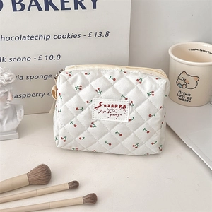 Vue détaillée d'une trousse à maquillage blanche matelassée avec un motif cerise