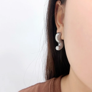 Boucles d'oreilles minimalistes argentées en forme de S en acier inoxydable portées sur modèle