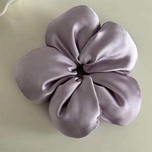 Close-up of a premium lavender satin flower scrunchie with a soft silk texture and luster