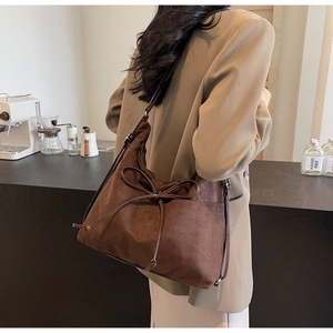 Detail of vintage dark brown suede tote bag with decorative bow in a cafe setting
