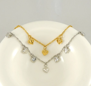 Detailed view of heart-shaped pendants with pleated texture in gold and silver finishes