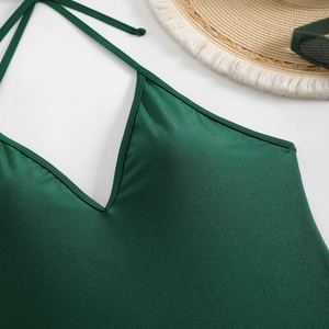 Deep green halter neck one-piece swimsuit with satin finish and backless design for women