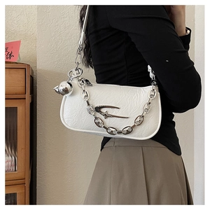 Detailed shot of white crinkled patent leather shoulder bag with silver chain and star logo