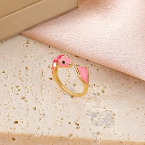 Adjustable golden ring with pink enamel fish design on a rustic stone background