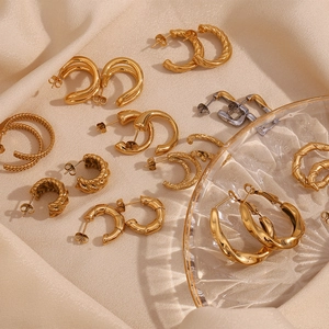 Mise à plat de boucles d'oreilles dorées vintage en forme de C sur satin de soie