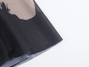 Gros plan sur la texture du tissu en maille noir et beige de cette robe longue sexy ajustée