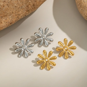 Detail view of 18k gold and silver flower stud earrings on natural stones