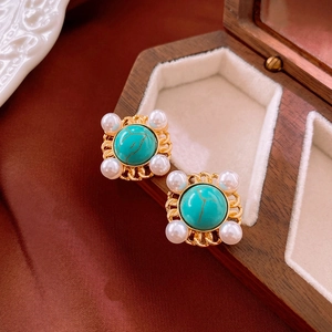 Macro detail of vintage gold square earrings with turquoise stone and white pearls