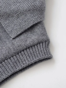 Detailed macro view of dark grey knitted texture and ribbed cuff design on sweater