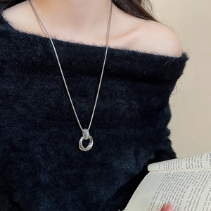 Close-up of multilayer silver circles pendant on a snake chain over a black sweater