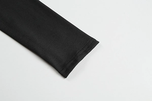 Detailopname van dubbelgestikte mouwboorden aan deze elegante zwarte nauwsluitende jurk