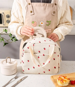 Dettaglio della borsa termica in velluto a coste crema con stampa fragole e tasca frontale