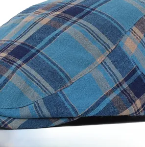 Detailed macro view of high-quality precision stitching on the blue and brown plaid flat cap