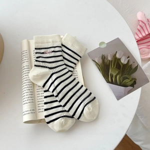 Detail of white cotton socks with black stripes and pink embroidered text on a book