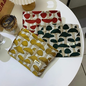 Three mushroom jacquard makeup bags in red, yellow and green on a white table