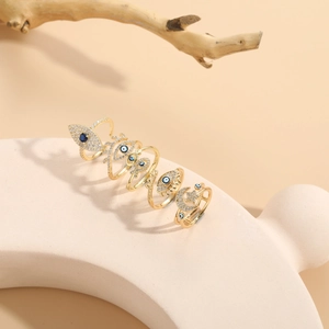 Detailed close-up of gold rings with evil eye and star motifs on a neutral prop