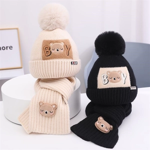Detailsicht auf gestrickte Bärenmützen und passende Schals in Beige und Schwarz