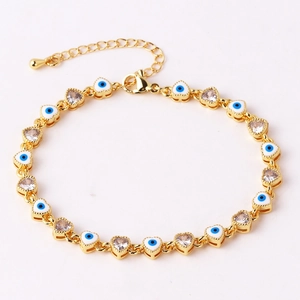 Macro view of gold heart chain bracelet with white enamel evil eyes and zircon stones