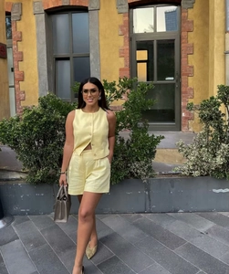 Outdoor shot of a women's yellow sleeveless button-front top and casual shorts set