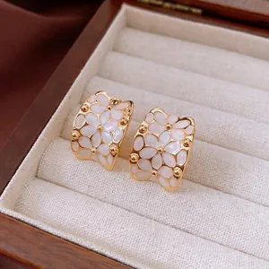 Elegant 18k gold plated floral stud earrings with white enamel petals in a jewelry box