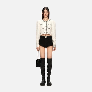 Close-up of white tweed jacket with black trim paired with black high-waisted shorts