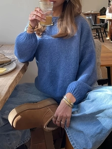 Maglione blu a girocollo in maglia abbinato a jeans e stivali marroni in un interno bar