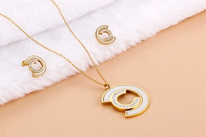 Detail of gold-plated jewelry set with C-shaped shell inlay on soft white plush fabric