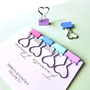 Macro detail of colorful macaron heart-shaped metal paper clips on a decorative card