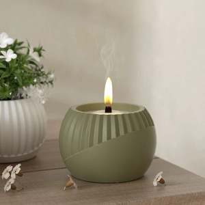 Detailed view of a burning wood wick candle in a sage green textured resin container