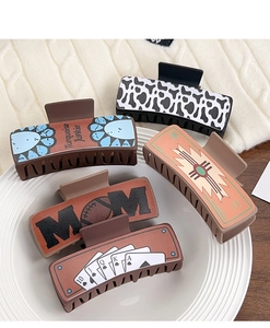 Detail view of five assorted western style claw clips with vintage leather patterns on a plate