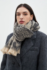 Close-up of grey and beige leopard print plush scarf with delicate fringe edges