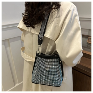 Detail of trendy rhinestone bucket bag with woven strap and shimmering silver crystals
